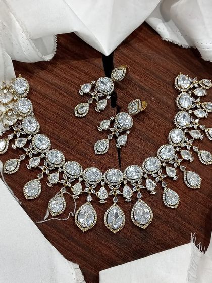 A stunning AD necklace set laid out to show its full design. This piece is available in multiple vibrant colors like ruby red, emerald green, pastel blue, and sapphire blue, featuring teardrop-shaped stones.