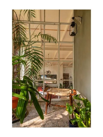 A quiet corner on the mezzanine level, where a woven chair sits by a large internal window overlooking the living space below.
