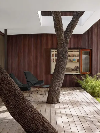 This design cleverly incorporates two trees into a covered patio. Cutouts in the floor and roof allow the trees to grow freely, providing natural shade and a sense of being completely immersed in the garden.