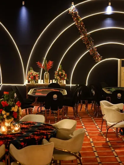 A wider view of the poker area, showing multiple tables set up for a large number of guests to enjoy the games simultaneously.