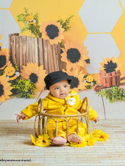Buzzing with cuteness, this baby is the star of a sunflower and bee-themed session. The bright yellow honeycomb backdrop, cheerful props, and the baby's happy expression make for a fun and vibrant photoshoot.