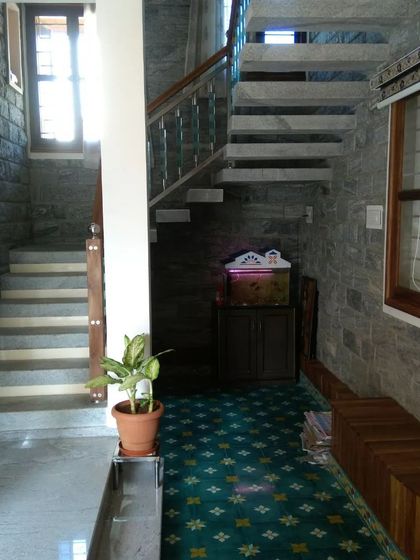 The interior of the Hemavathi and Hareesh residence, showcasing cool-toned stone walls and a patterned floor runner.