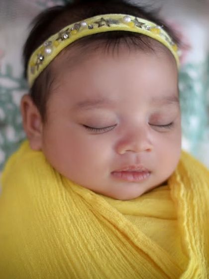 A close-up on pure beauty. This portrait focuses on the delicate features of a sleeping newborn, wrapped in a sunny yellow swaddle that makes her glow.