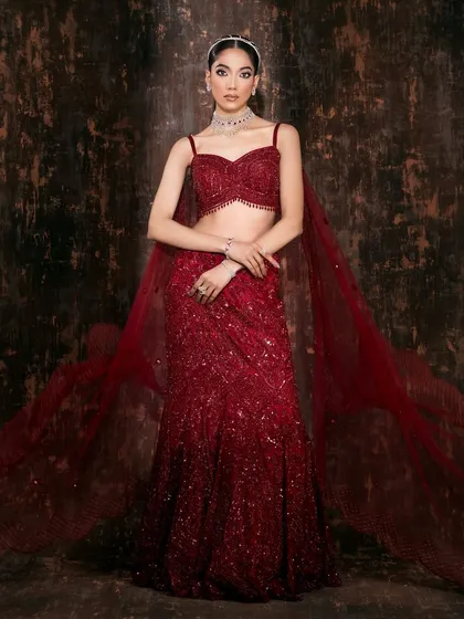 The full vision of a modern bridal look. The movement in the flowing red lehenga and the confident pose create a powerful silhouette against a moody, textured backdrop. This is how we build a complete story for a designer's collection.