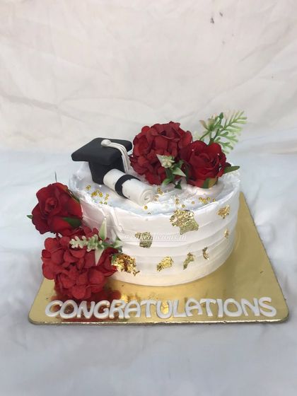Because every milestone deserves a celebration. This elegant cake was for a graduation, featuring a fondant graduation cap, a diploma, and beautiful red flowers.