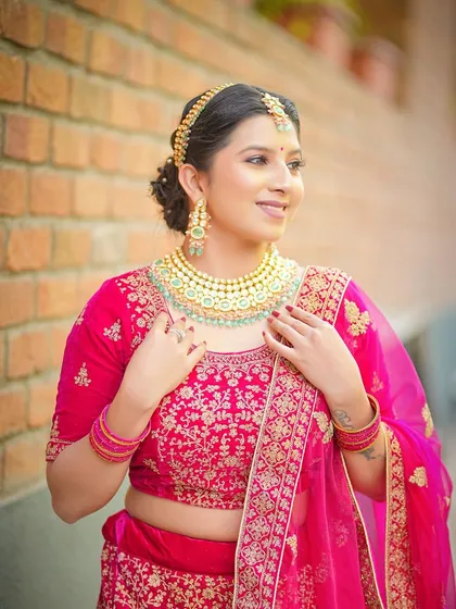 A smiling portrait of the model, her makeup soft and pretty to complement the bright lehenga.