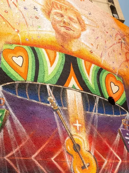 A close-up of the Ed Sheeran mural, focusing on the guitar and the heart motifs. The textured paint and bright colors are clearly visible in this detailed photograph.