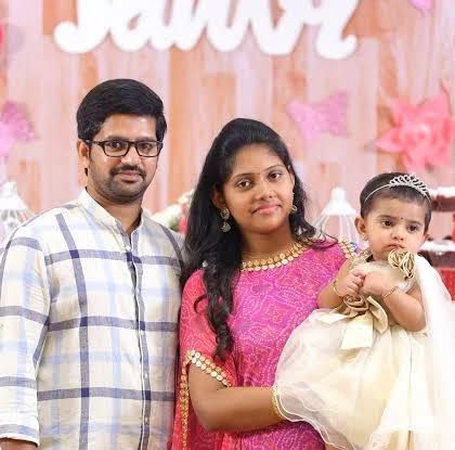A family portrait taken at a first birthday party with a beautifully decorated dessert table in the background.