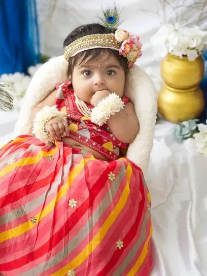 A curious moment from our little Radha. The combination of peacock feathers, golden pots, and soft white fabrics creates a divine setting.