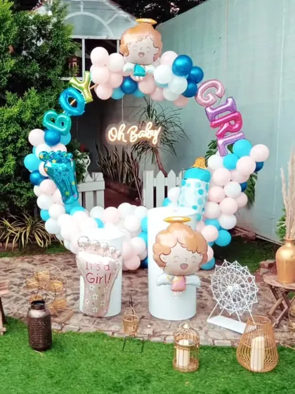 A fun gender reveal or baby shower setup. The decor features a circular balloon arrangement with "Boy" and "Girl" foil balloons, along with other baby-themed props in a pink and blue color scheme.