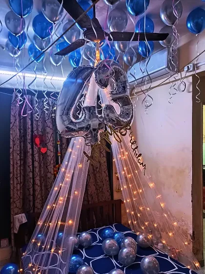 A canopy decoration over a bed using net fabric and fairy lights. Combined with number foils and ceiling balloons, it's a wonderful birthday morning surprise.
