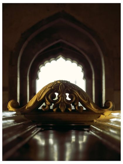 A beautifully composed shot from inside Safdarjung's Tomb, looking out through a series of arches. The carved marble cenotaph is perfectly framed, creating a sense of depth and history.