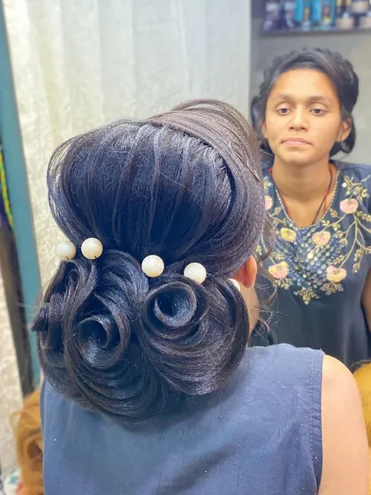 A classic low bun made of hair roses and accented with large pearls. This is a timeless and elegant choice for brides, bridesmaids, or mothers of the bride.