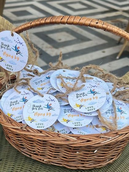 A basket of custom "Thank you for flying by" tags, ready to be attached to first birthday party favors.