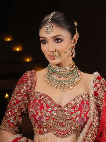 A powerful portrait against a dark background, making the bride's features and the vibrant red of her lehenga pop. The candlelit ambiance adds to the royal, intimate feel.