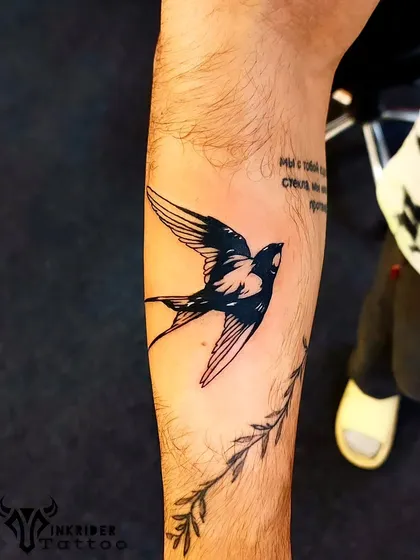 A classic black and grey swallow tattoo, a traditional symbol of travel and return. The shading gives the bird a sense of movement and life.