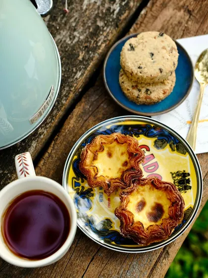 A quiet moment with a cup of chai, our Nutty Nankhatai, and some crispy Pastel de Nata. It's the perfect way to take a break during a rainy afternoon.