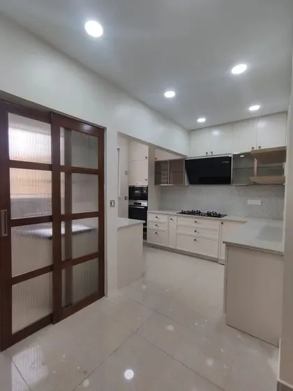 A completed kitchen in Bangalore, featuring a wooden sliding door with glass panels that can separate the kitchen from the utility area when needed.