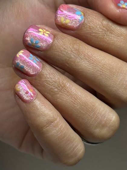 A fun and summery design featuring a shimmery pink base with small, colorful, hand-painted flowers scattered across the nails.