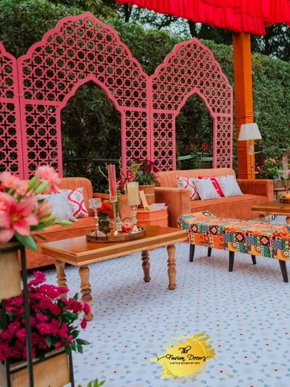 A wide view of the Mehendi seating area, showing how the pink jaali panels, orange sofas, and patterned textiles come together to create a cohesive and vibrant look.