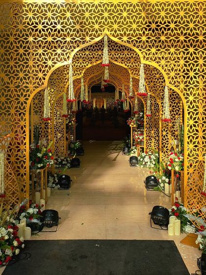 This grand entrance features Moroccan-style golden jaali arches, creating an exotic and regal path. The walkway is lined with floral arrangements, making guests feel like they are entering a palace.