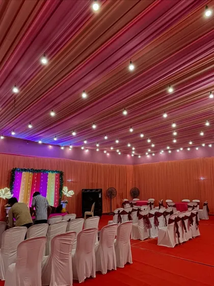 This is a full view of an indoor hall setup for a Mehendi ceremony. We used vibrant ceiling drapes and string lights to create a festive atmosphere, with organized seating for all the guests.