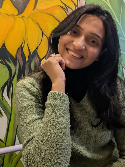 Posing with a smile against a vibrant sunflower mural.