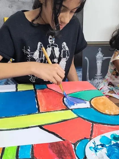 A student applies bold colors to a large canvas, learning about abstract shapes and color blocking. Our classes cover a wide range of artistic styles and techniques.