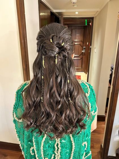 A bohemian-inspired half-up style with soft waves, mini braids, and delicate gold feather accessories.