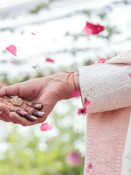 A symbolic and artistic shot of a ritual, with rose petals being showered over the couple's joined hands. This image captures the beauty and sanctity of wedding traditions.