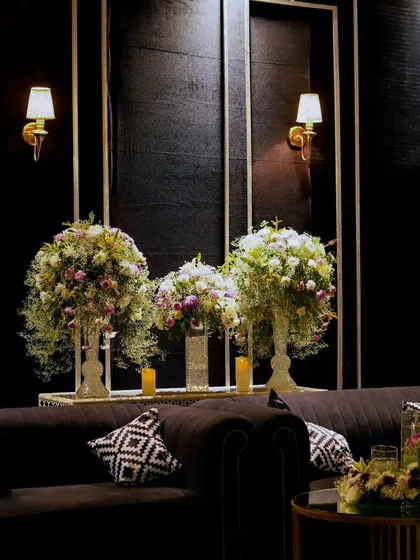 Plush black velvet sofas are accented with geometric pillows and lush white floral arrangements, creating a comfortable yet incredibly stylish seating area.