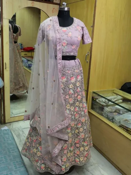 A beautiful lavender lehenga with colorful floral embroidery. This piece, shown on a mannequin, is perfect for a spring wedding or engagement.