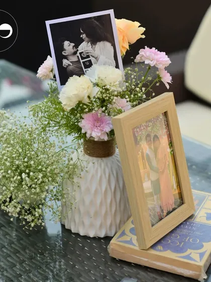 A table centerpiece featuring a mix of family photos, a sonogram picture, and fresh flowers, creating a deeply personal and touching display.