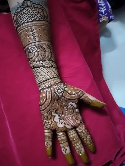This intricate design was for the bride's sister. It features peacock motifs and detailed patterns that extend up the arm, perfect for a close family member who wants a grand look.