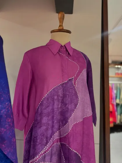 A close-up of a purple dress with textured, color-blocked panels, showcasing its unique design.