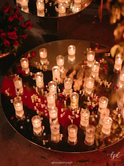 A detail shot of votive candles on a mirrored surface, reflecting the warm glow and adding a layer of intimacy and sparkle to the wedding decor.