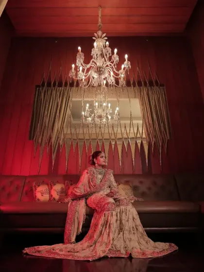 Crafting cinematic moments for our brides is our passion. This portrait, set against a backdrop of dramatic red drapery and a single majestic chandelier, showcases how we use decor to create regal, magazine-worthy photographs.