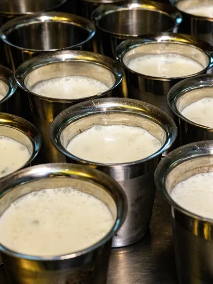 Rows of traditional steel glasses filled with buttermilk for an Onam sadhya. This image captures a cultural detail that tells the story of the special event at Kari Apla.