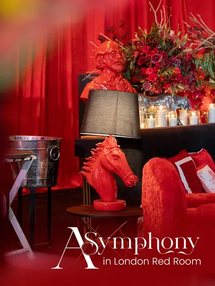 "A Symphony in London Red Room". This image captures the essence of the theme, with a red horse head sculpture, a modern lamp, and lush floral arrangements creating a chic and dramatic vignette.