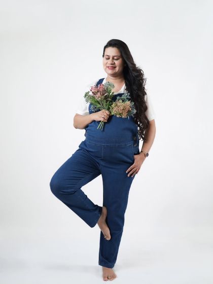 A full-length shot of our client enjoying her casual maternity shoot in denim overalls. This pose is playful and shows off her happy, confident energy.