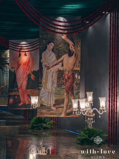 The entrance pathway lined with scrolls of Raja Ravi Varma's paintings. This creative entryway provides guests with a unique and immersive introduction to the event's theme.