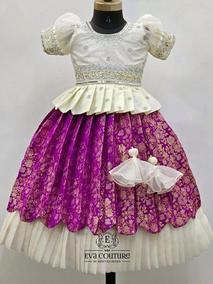 A beautiful white and purple Banarasi lehenga. The white peplum blouse is paired with a rich purple brocade skirt with a double-layered hem.