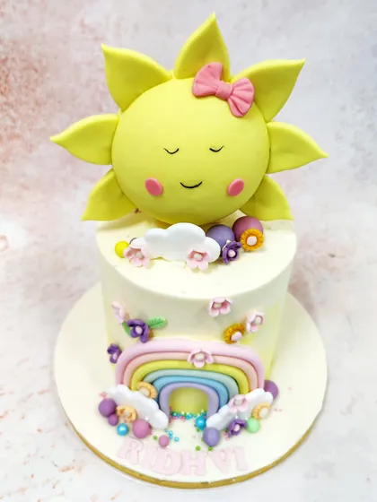 Another view of the sun and rainbow cake, showing the scattered flowers and colorful bead details.