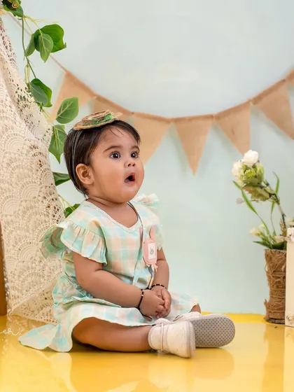 A look of pure wonder. This first birthday studio portrait captures the curiosity of a one-year-old with a soft, celebratory backdrop.