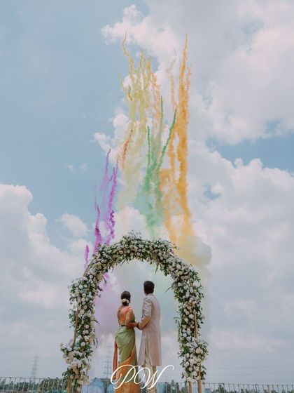 A truly epic shot of the couple's exit, framed by a floral arch with a rainbow of smoke bombs painting the sky. This is how you make a statement.