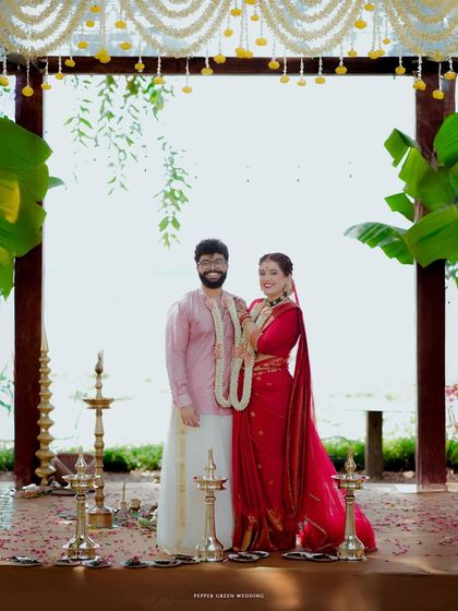 A stunning portrait of the bride and groom at their mandap, set against the serene Kerala backwaters. The traditional decor and their elegant attire create a picture-perfect moment.