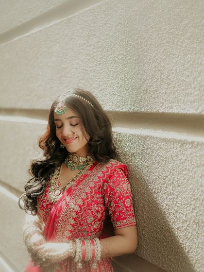 A portrait of pure bliss. The bride leans against the wall, eyes closed with a happy smile, basking in the sunlight and the joy of her wedding day.