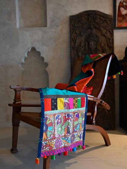 The green silk runner draped over a chair, showing how it can be used as a decorative throw to add a pop of color and texture to a room.