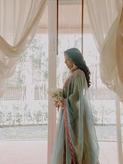 An ethereal portrait of Pallavi at her Thailand wedding. The flowing white curtains frame her beautifully against the light, creating a soft, dreamy, and angelic image.