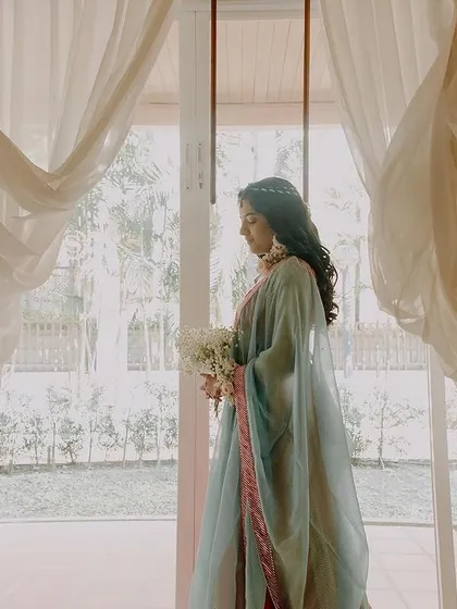 A dreamy and ethereal bridal portrait. The bride is framed by flowing white curtains, creating a soft, romantic, and almost painterly image that is simply breathtaking.